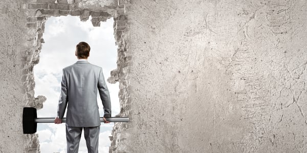 Young businessman with big hammer against wall